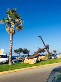 Palm trees by road against clear blue sky