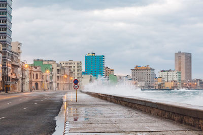 Road by buildings against sky in city