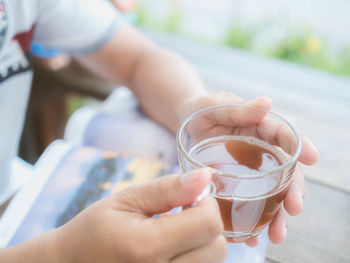 Midsection of woman holding tea at wooden table