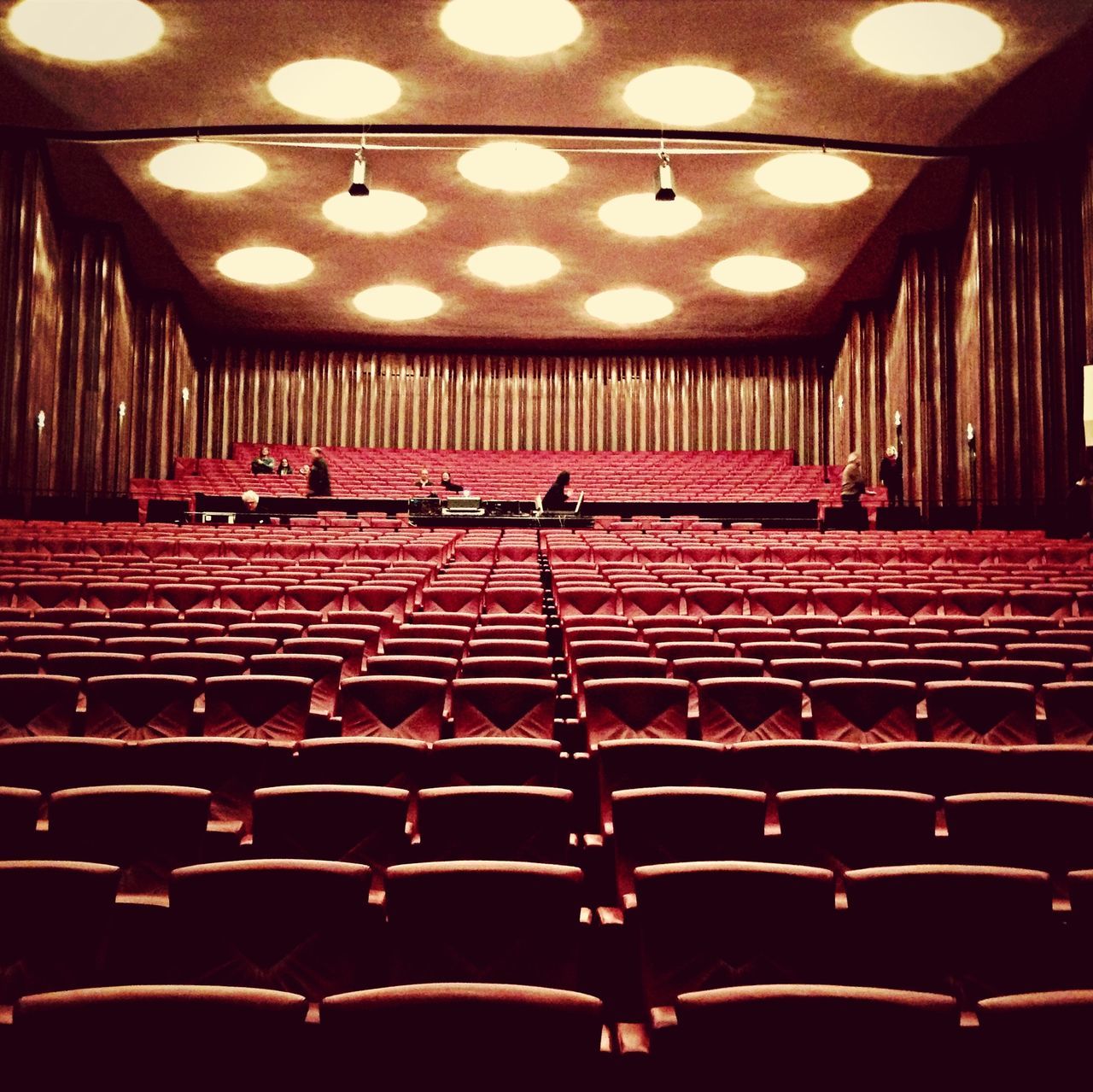 indoors, illuminated, in a row, ceiling, lighting equipment, repetition, order, large group of objects, hanging, arrangement, empty, red, absence, pattern, chair, abundance, no people, side by side, seat, design