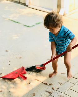 High angle view of boy sweeping at yard