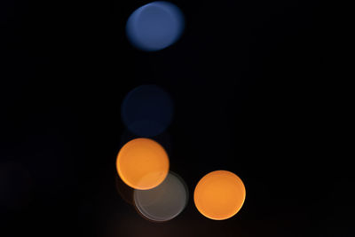 Low angle view of illuminated lighting equipment against black background