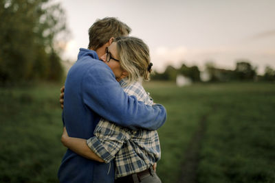 Mature couple hugging each other on field during sunset