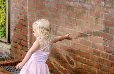 Girl standing against brick wall