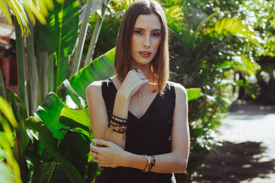 Portrait of beautiful young woman standing against plants