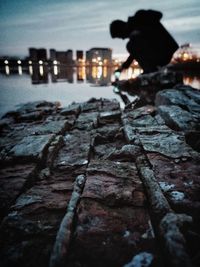 Man on rock by sea against sky at night