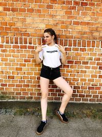 Portrait of a young woman standing against brick wall