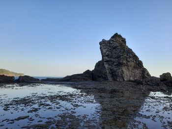 Rock formations in sea against clear sky