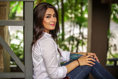 Portrait of young woman sitting on railing