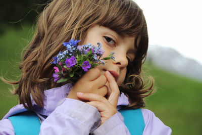 Close-up portrait of cute girl holding flowers