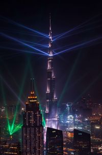 Illuminated burj khalifa in city against sky at night