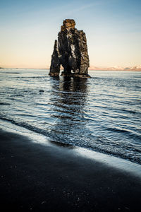 Rock formation on beach against sky during sunset