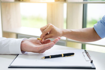 Hands of couple holding ring over clipboard