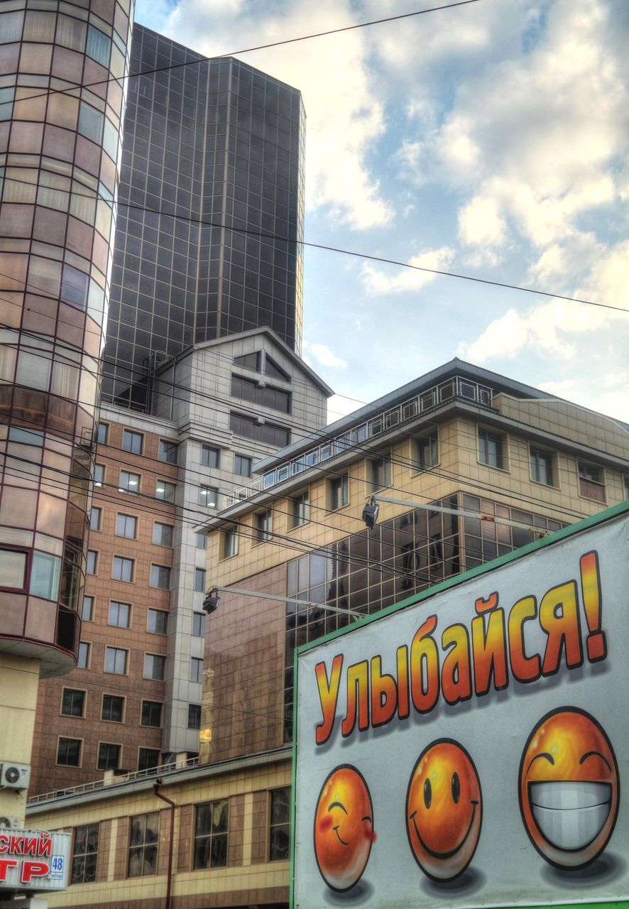 building exterior, architecture, built structure, sky, low angle view, city, building, text, cloud - sky, window, western script, residential building, cloud, glass - material, communication, outdoors, day, no people, cloudy, city life