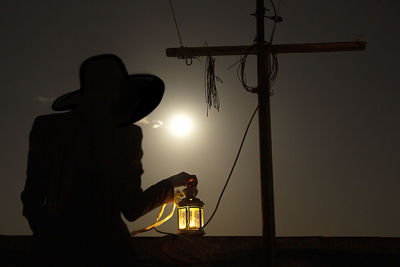 Figure of a woman on a full moon night with a candle light in her hand on a terrace