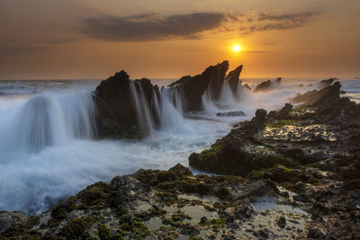 Scenic view of waterfall against sky during sunset