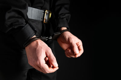 Midsection of man gesturing against black background
