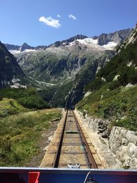 Railroad tracks amidst mountains against sky