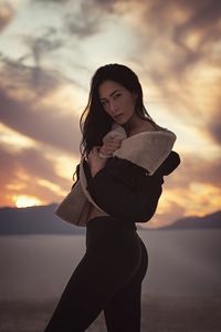 Portrait of woman standing against sky during sunset