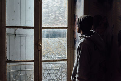 Rear view of a man looking through window