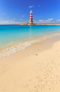 Lighthouse by sea against sky