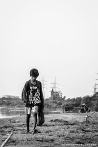 Full length of teenage girl standing on field against clear sky