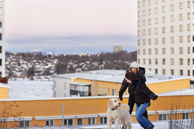 Female couple walking dog in modern neighborhood