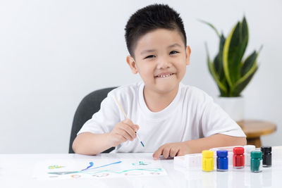 Portrait of smiling boy holding table at home