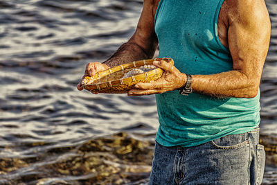 Midsection of man holding ice cream at beach