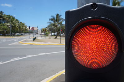 Close-up of red stoplight by road in city