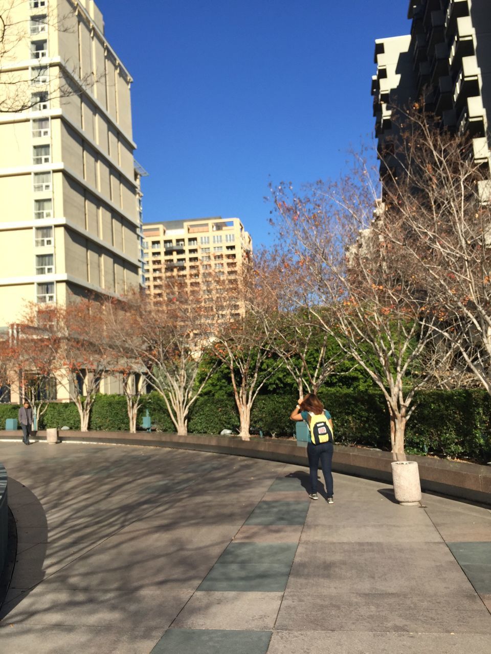 city, building exterior, built structure, architecture, sunlight, outdoors, real people, one person, full length, day, skyscraper, clear sky, tree, adults only, people, sky, adult, one man only, only men