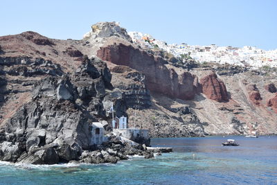 Rock formations by sea against clear sky