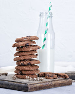 Stack of chocolate chip cookies by milk bottle against white background