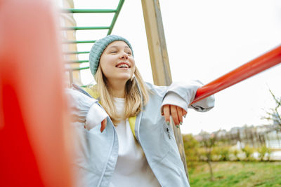 Happy teenage girl wearing knit hat standing at playground