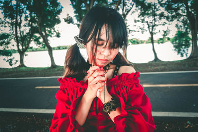 Portrait of girl holding red umbrella against plants