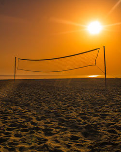 Volleyball net at beach during sunset