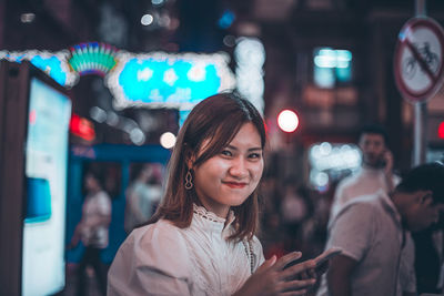 Portrait of smiling young woman standing in city