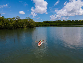 Rear view of woman with dog on lake against sky