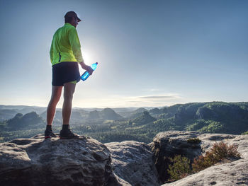 Fit runner in sport suit drinking the water from sport bottle with relax action in forest in morning