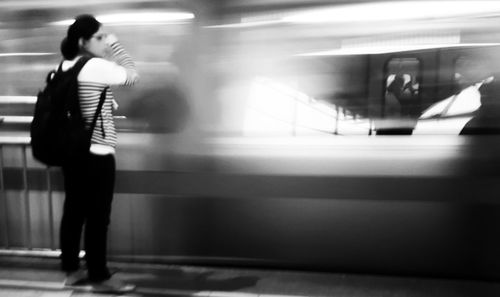 Rear view of woman standing at railroad station