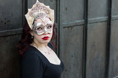 Close-up of woman wearing venetian mask against wall
