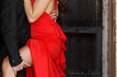 Midsection of couple standing against red wall