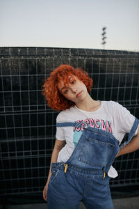Young alternative redhead girl posing in a black fence