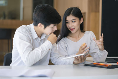 Young couple looking at camera while sitting on table