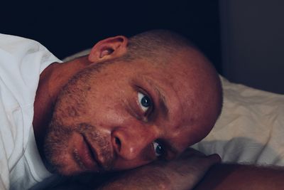 Close-up portrait of man lying down on bed at home