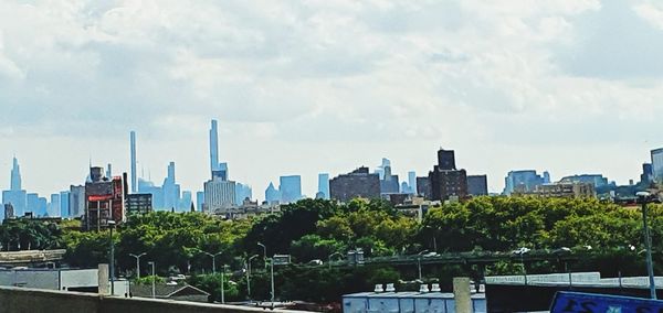 Trees and buildings in city against sky