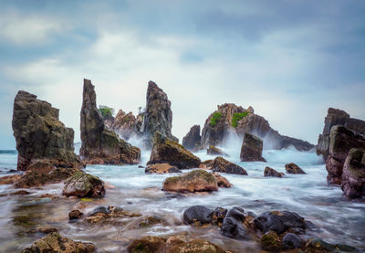 Scenic view of rocks in sea against sky