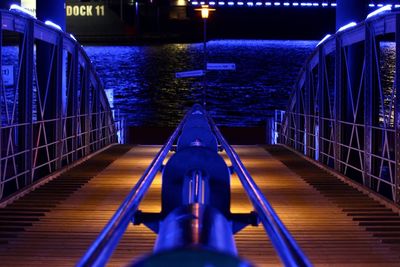 Illuminated bridge leading towards river during night