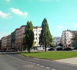 Cars on road by city against sky