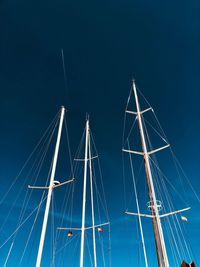 Low angle view of sailboat masts against blue sky